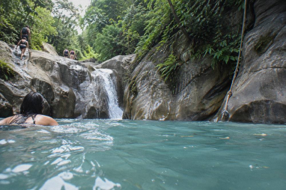 A calm turquoise pool between rock walls, framed by tropical forest