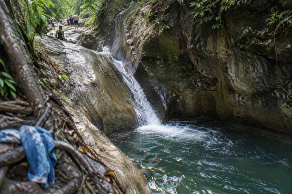 A narrow rock chute funneling water into a deep green pool
