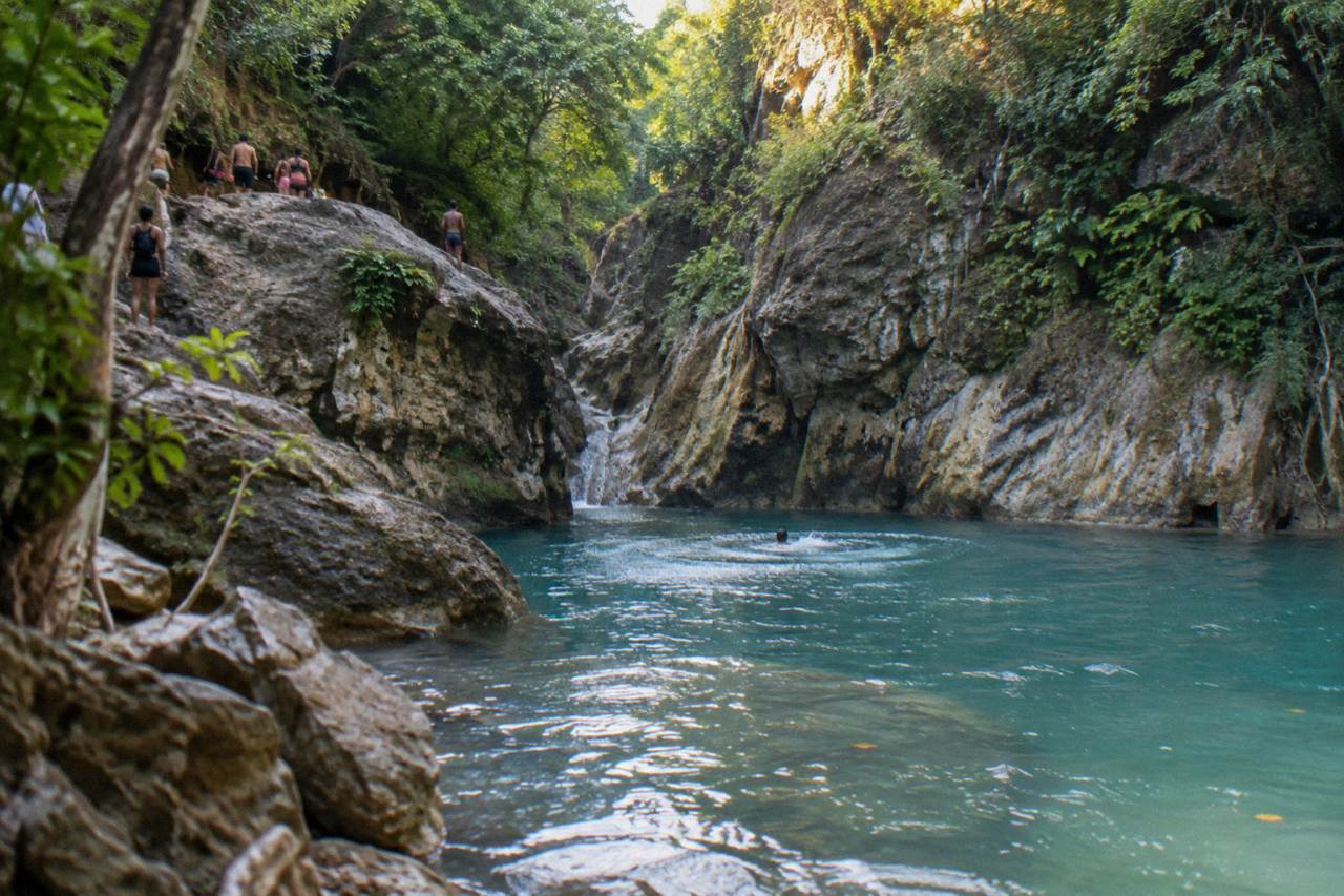 Turquoise waterfall pool in a narrow forested canyon at Damajagua
