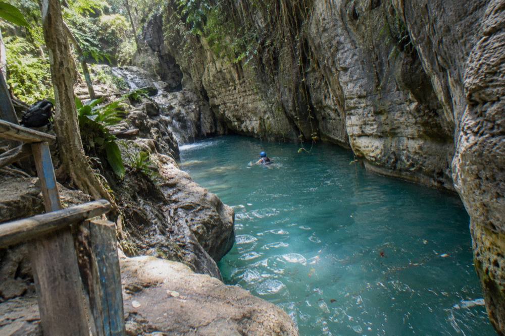 Turquoise waterfall pool enclosed by limestone canyon walls in a tropical forest