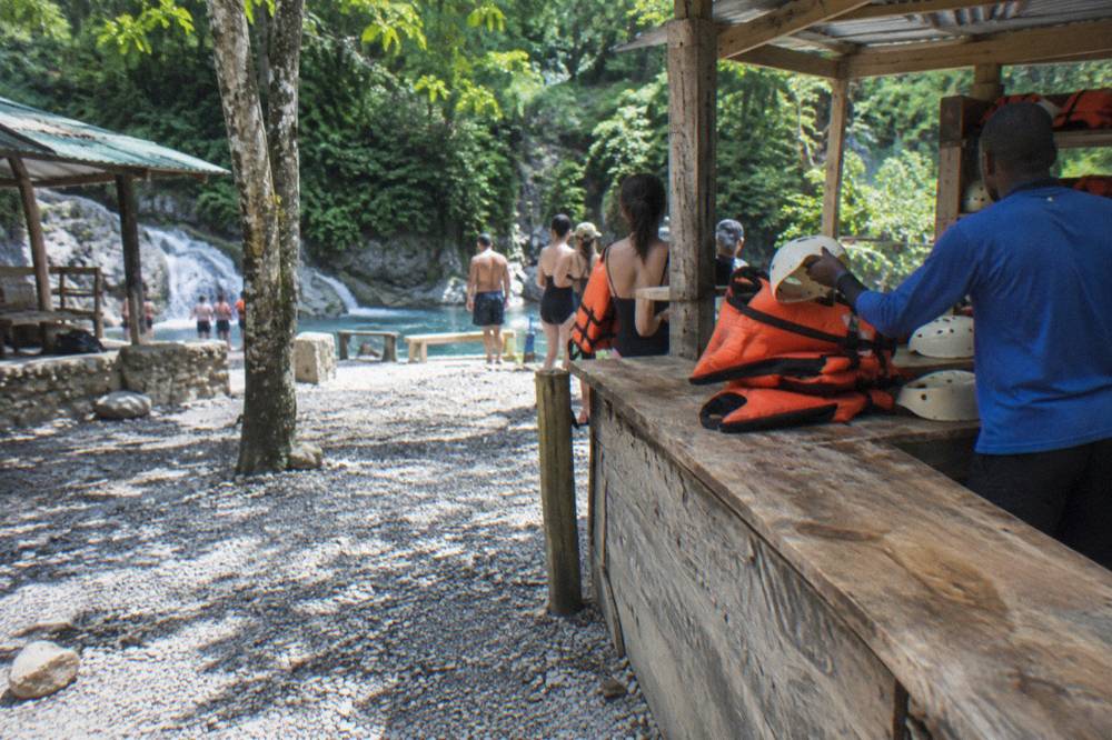 A tour guide handing helmets and life jackets to visitors at a forest visitor center