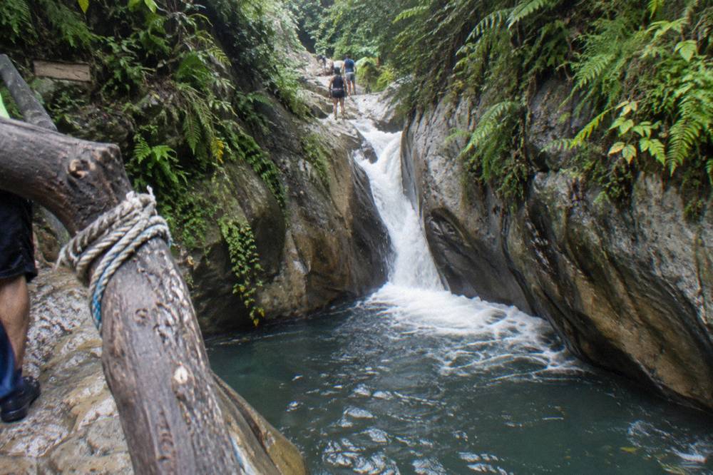 Guide in helmet and life vest demonstrating a slide position at the top of a rock chute