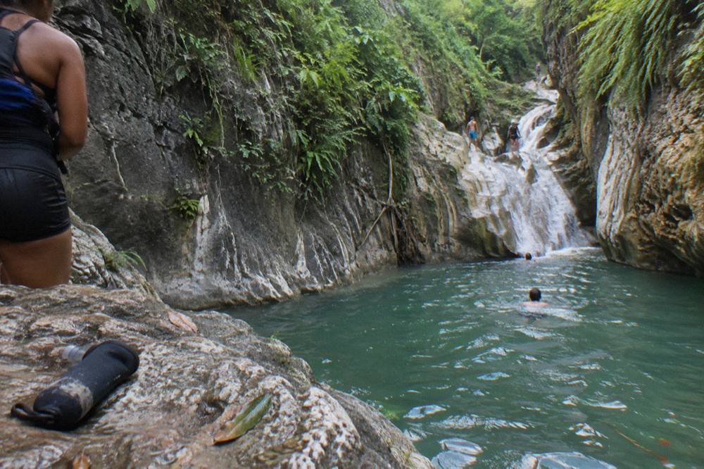 Canyon walls rising above a clear green pool at the Damajagua waterfalls