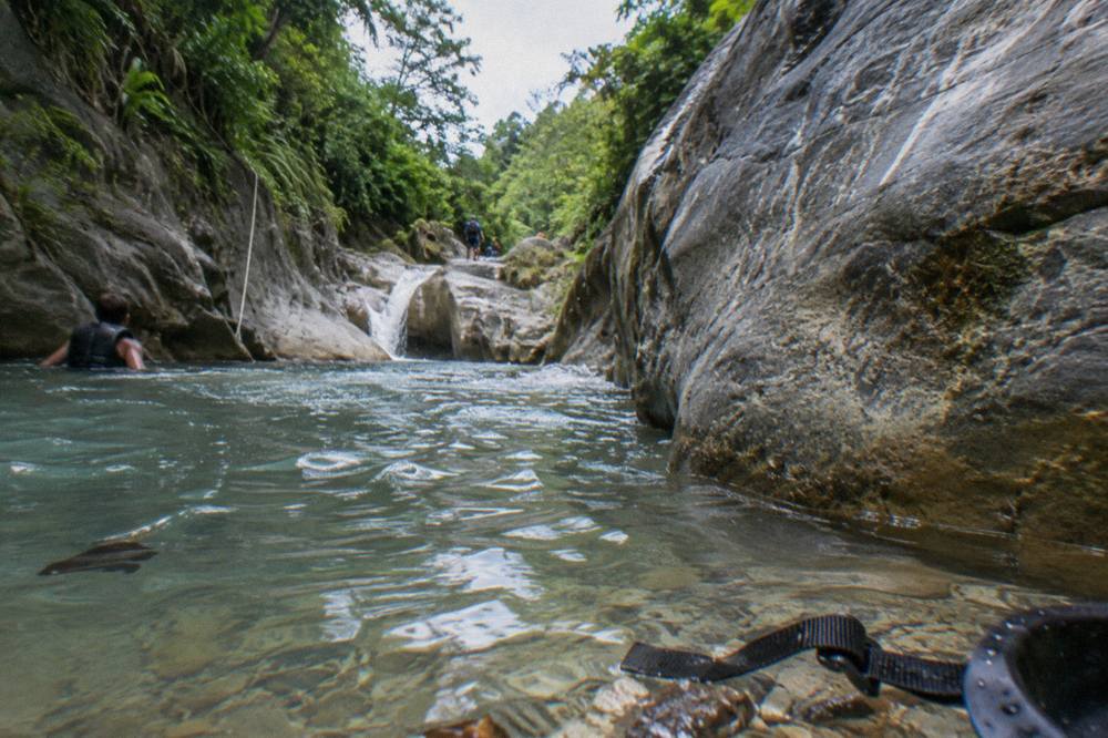 Narrow canyon passage with clear shallow water running between smooth rock walls