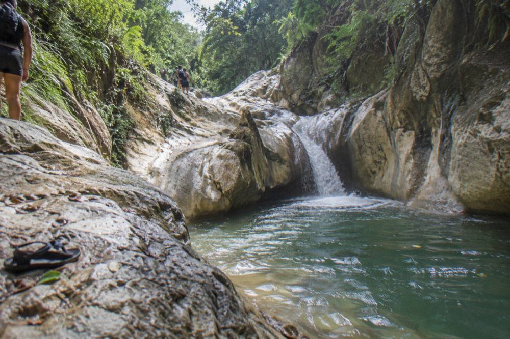 A canyon river winding between smooth rock walls with a cascade falling into a green pool