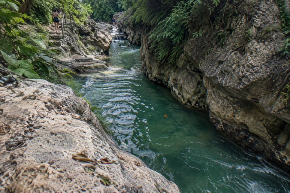 Canyon river running between tall rock walls with clear green water