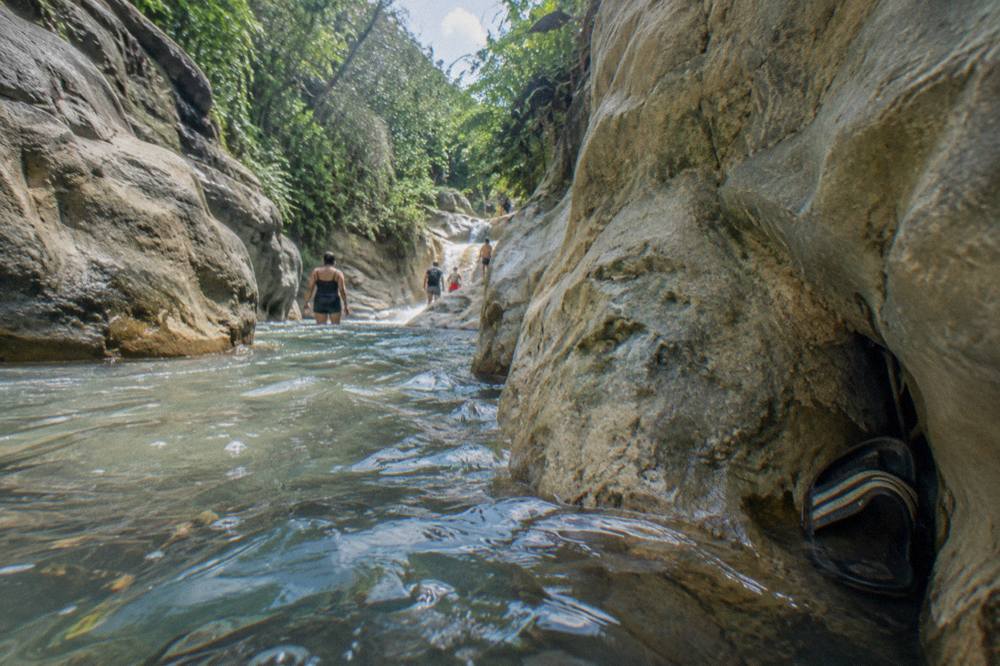 Narrow canyon passage with clear water flowing between rock walls