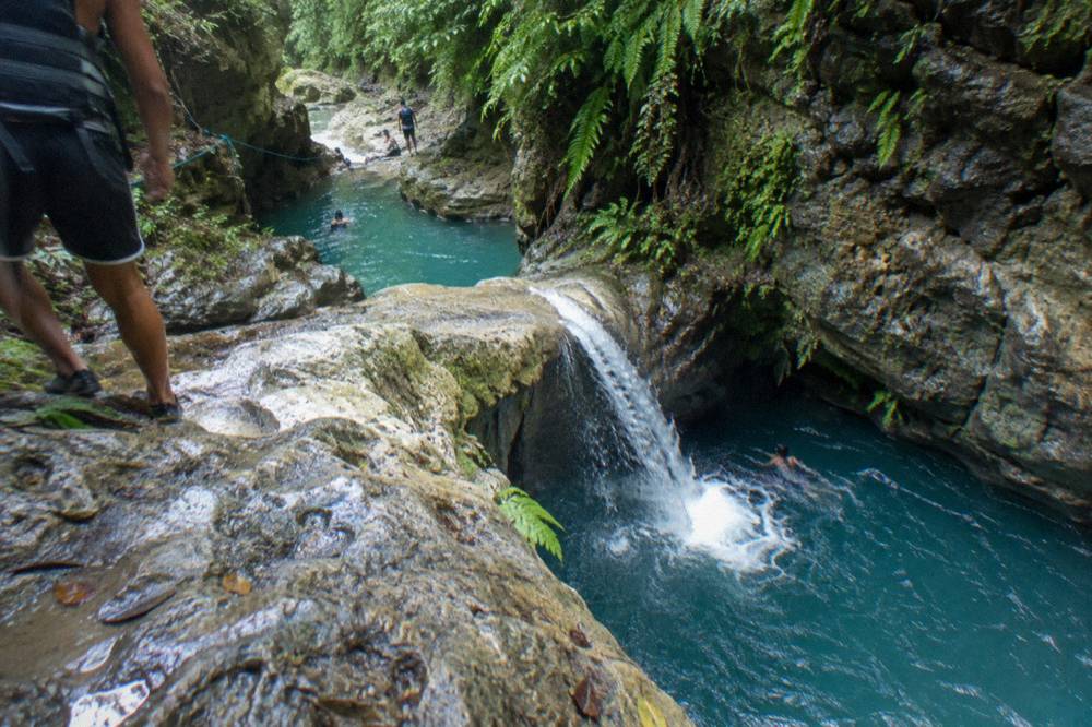 Narrow canyon with a waterfall pouring into a deep turquoise pool between rock walls