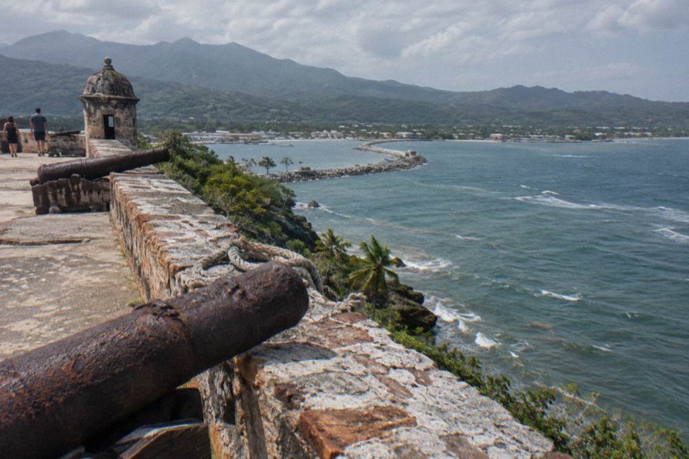 Stone fortress walls with old cannons overlooking a harbour and calm sea