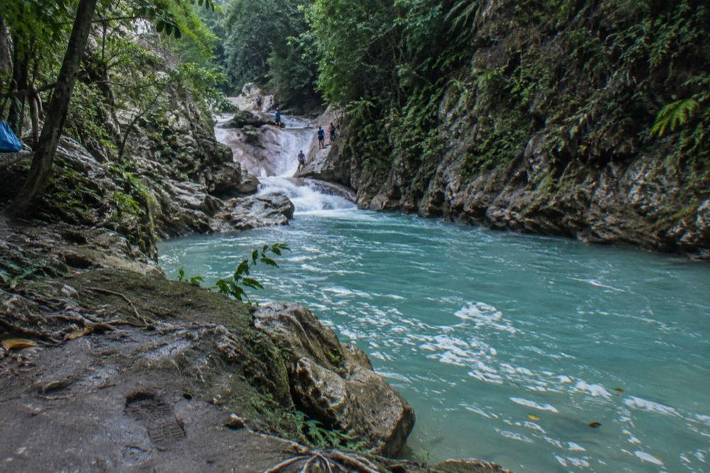 Wooded canyon with turquoise water sliding between rock walls