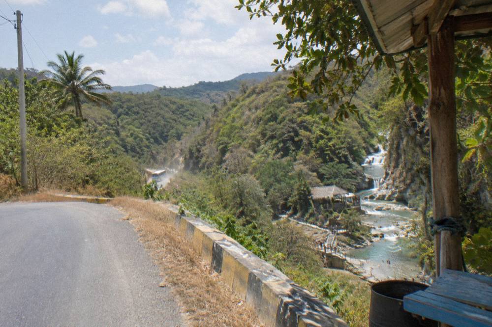 Winding mountain road through green hills above Imbert toward the waterfall entrance