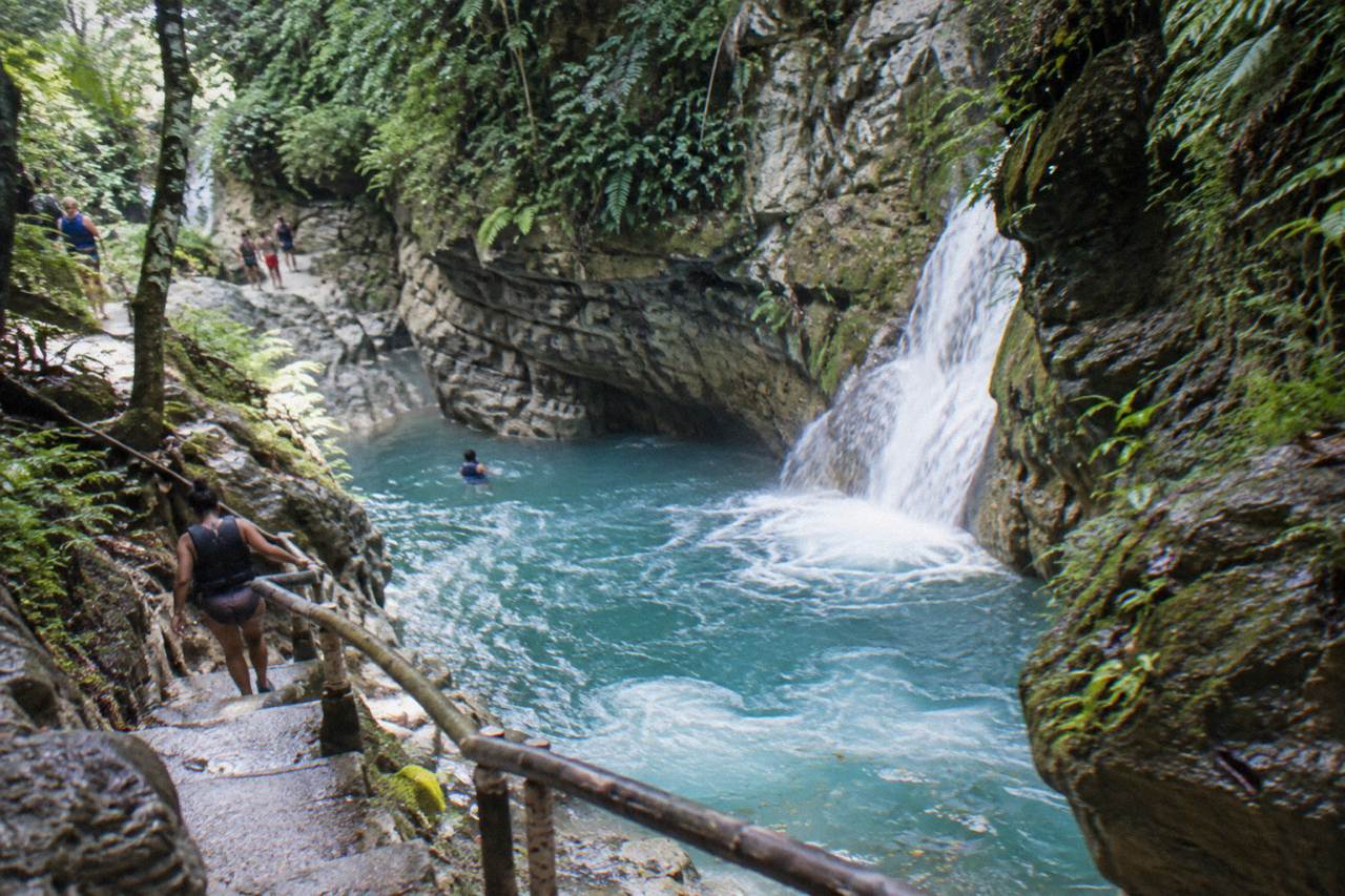 Turquoise waterfall pool between forested rock walls at the Damajagua river canyon