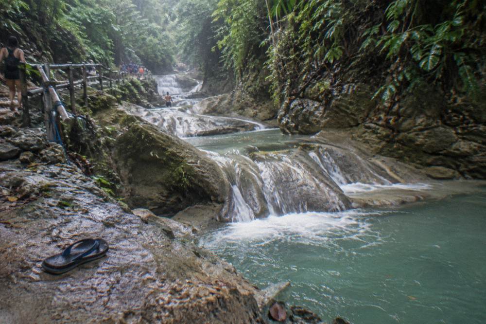 Stepped series of small waterfalls and pools descending through jungle canyon