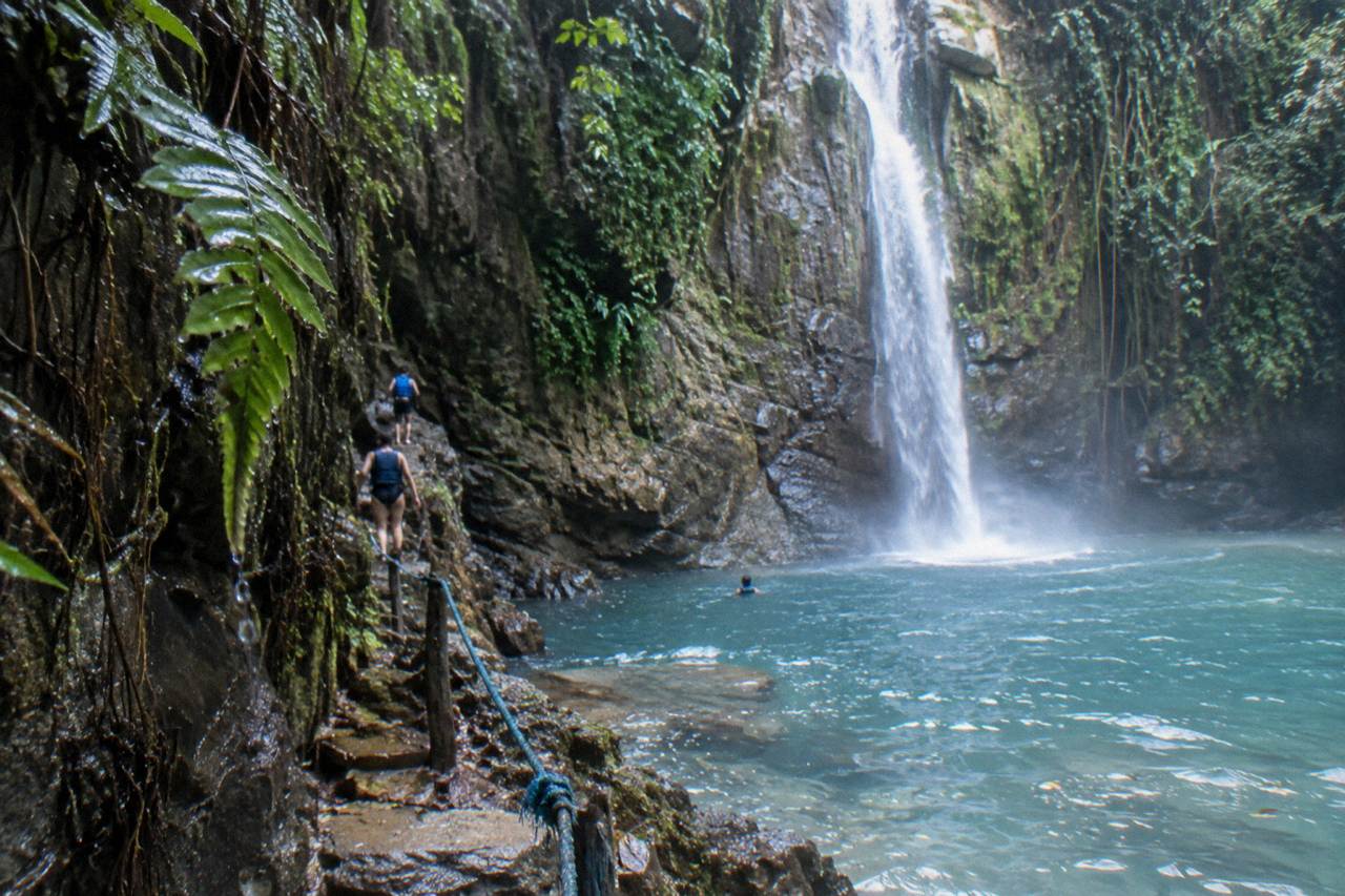 Turquoise pool at the base of a rock canyon waterfall surrounded by tropical forest