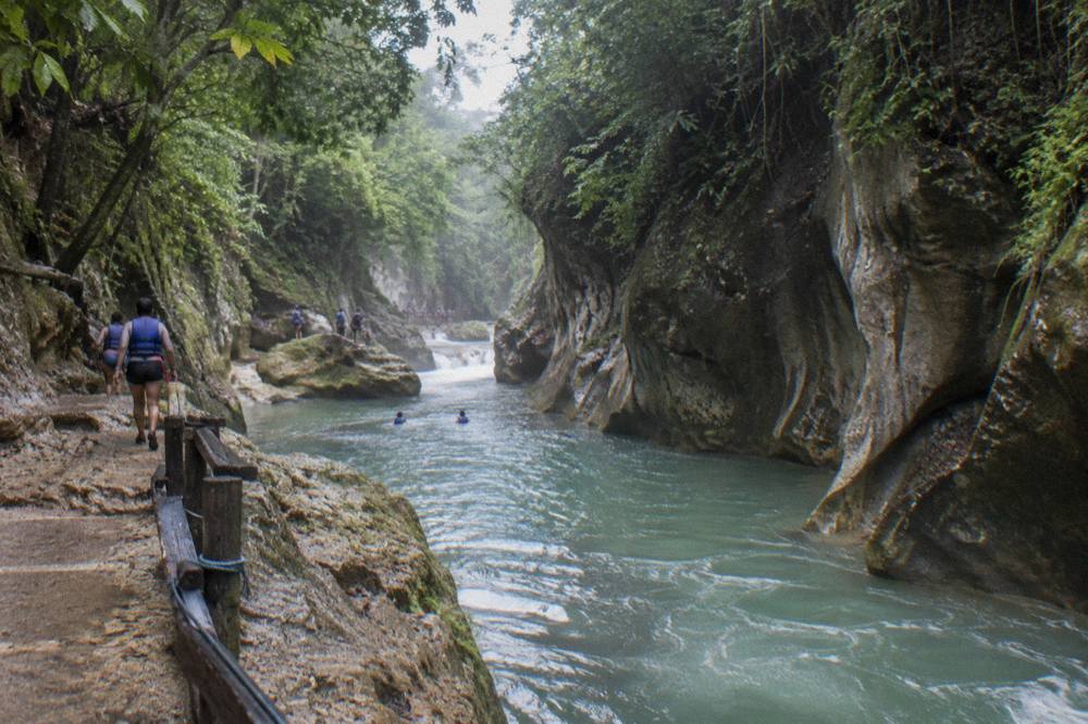 Canyon river winding between tall rock walls with dense green vegetation above