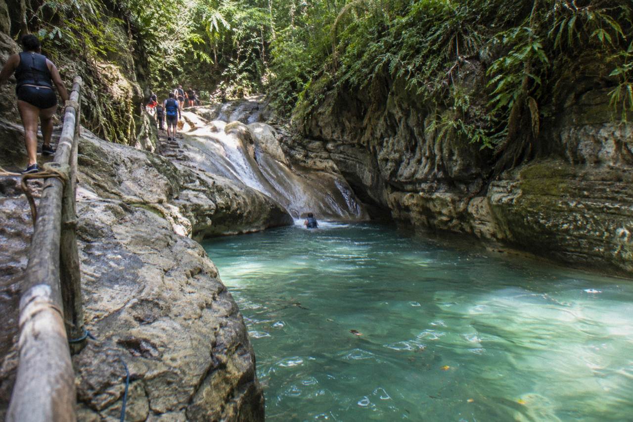 Turquoise waterfall pool framed by rocky canyon walls in a tropical forest