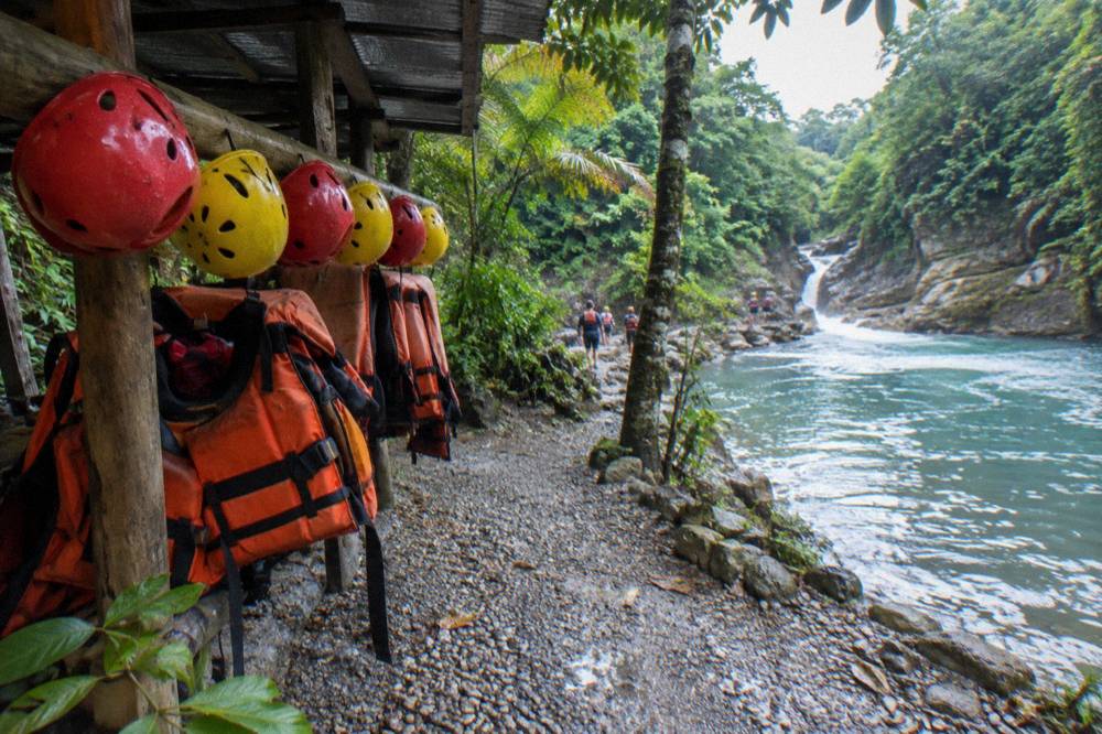 Helmets and life jackets hanging on a rail beside a forest trail