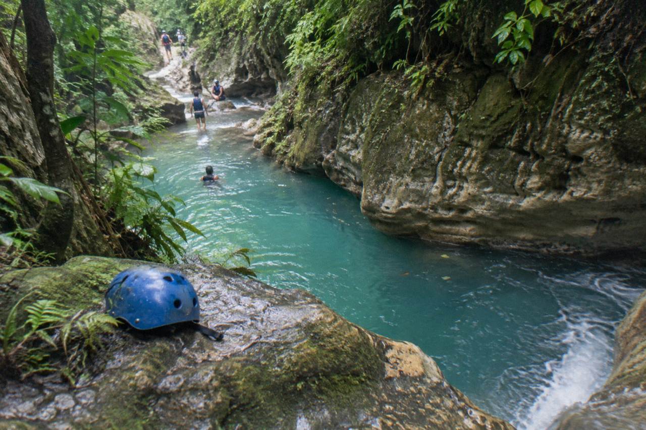 Turquoise waterfall pool in a narrow forest canyon at Damajagua
