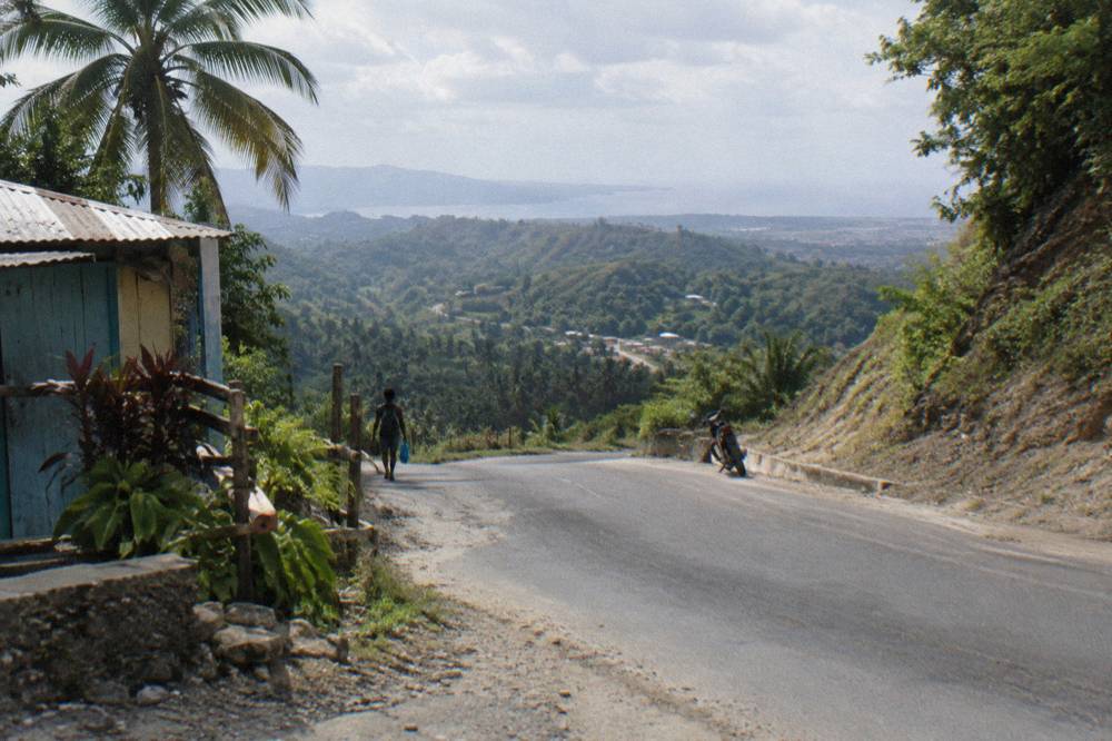 Winding rural road through green hills toward a mountain valley