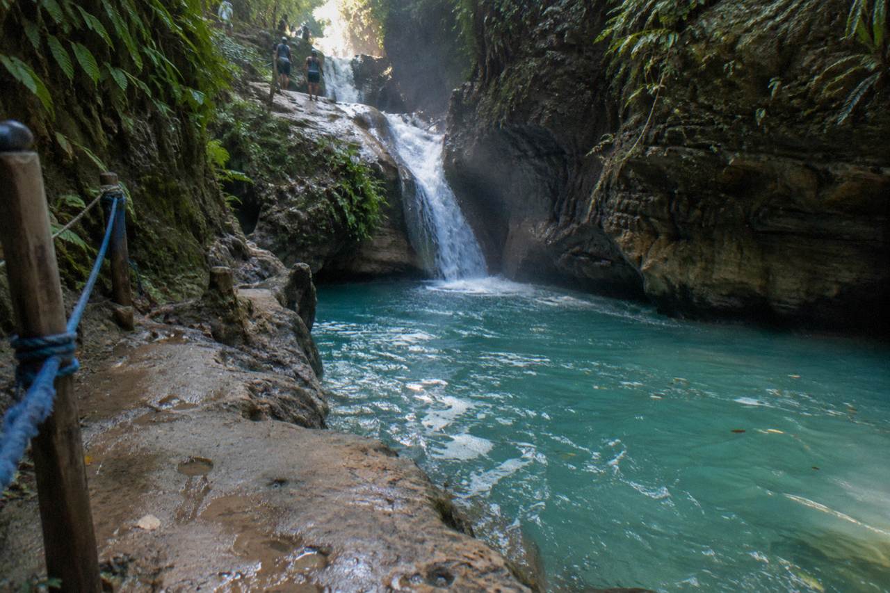 Turquoise waterfall pool in a narrow forested canyon at Damajagua