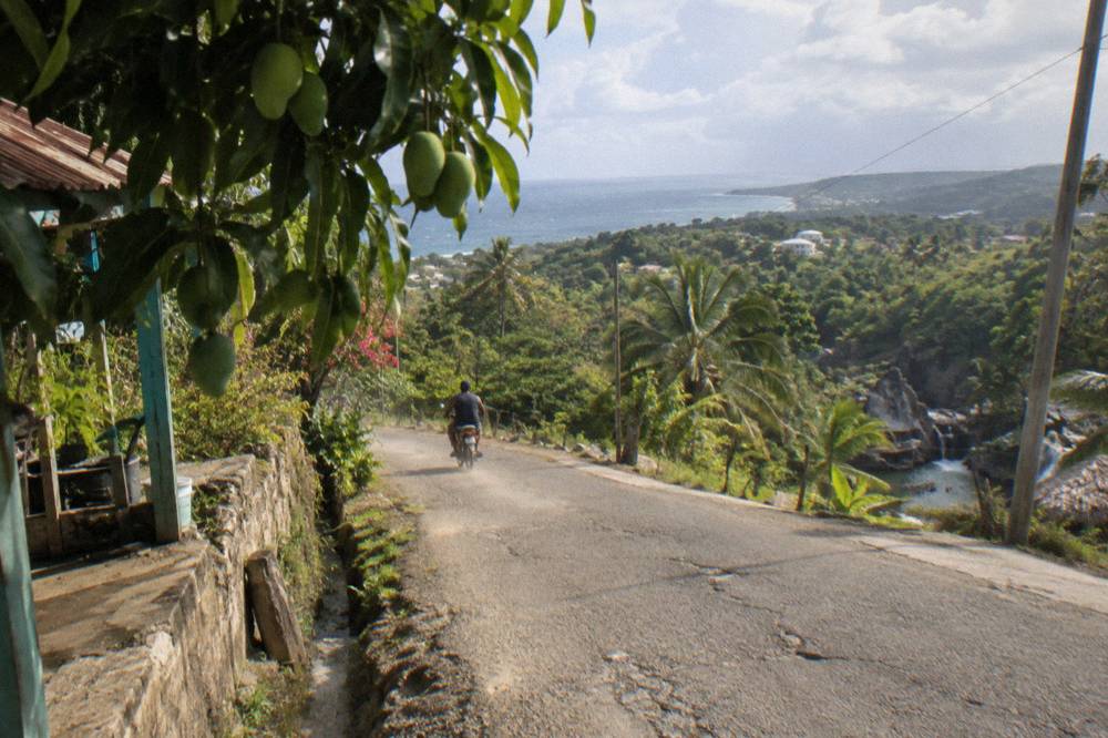 Rural road winding through green hills toward a small Dominican town