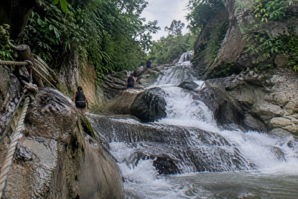 Canyon walls rising above a series of cascading waterfalls at Damajagua