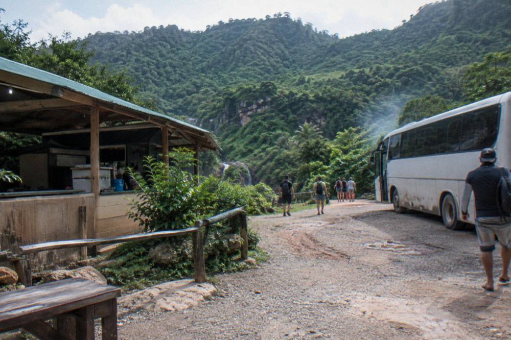 Tour bus parked at the Damajagua site with canyon hills behind