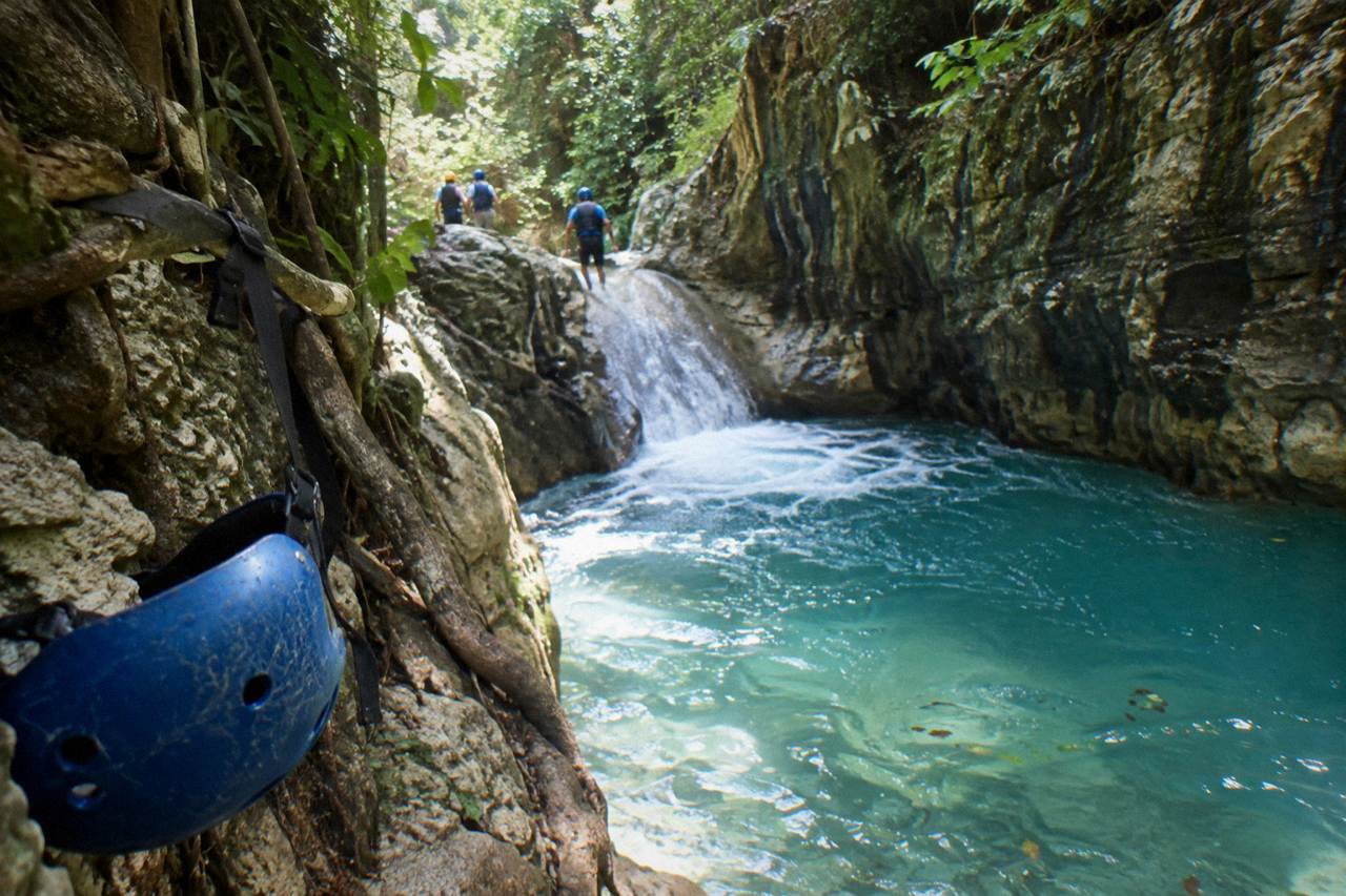 Turquoise waterfall pool in a narrow forested canyon at Damajagua