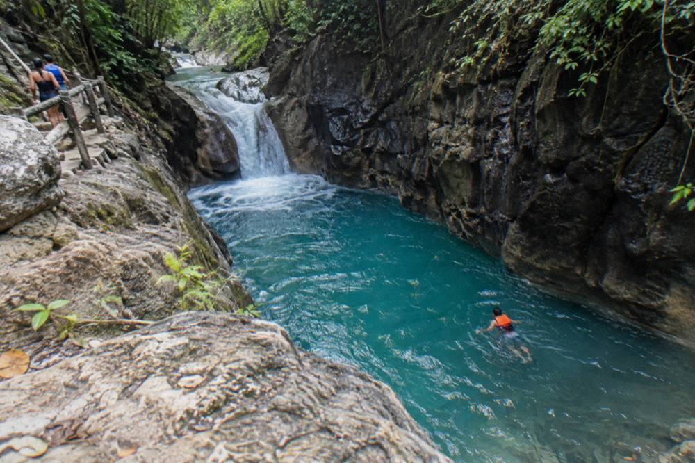 Swimmer in a life jacket floating in a turquoise pool between canyon walls