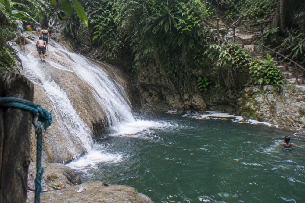 Cascading white water sliding over smooth rock into a green pool