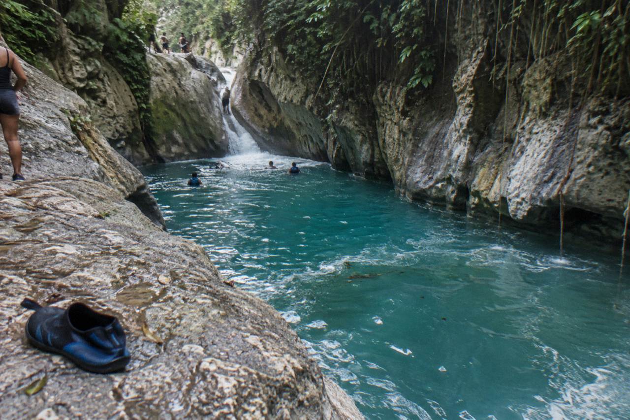 Turquoise waterfall pool in a narrow forested canyon at Damajagua
