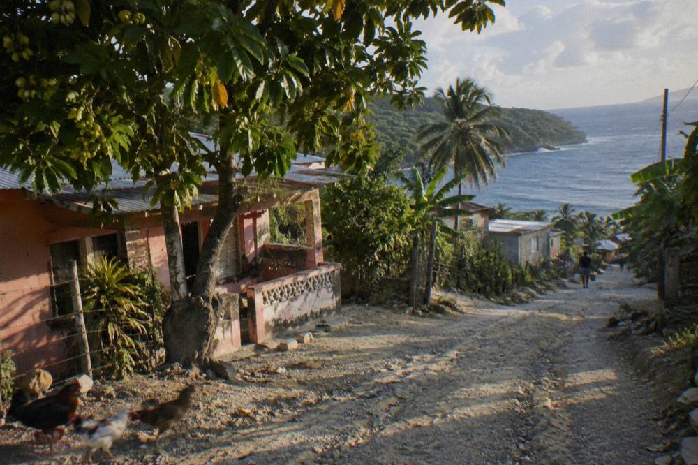 Country road winding through green hills toward a small Dominican town