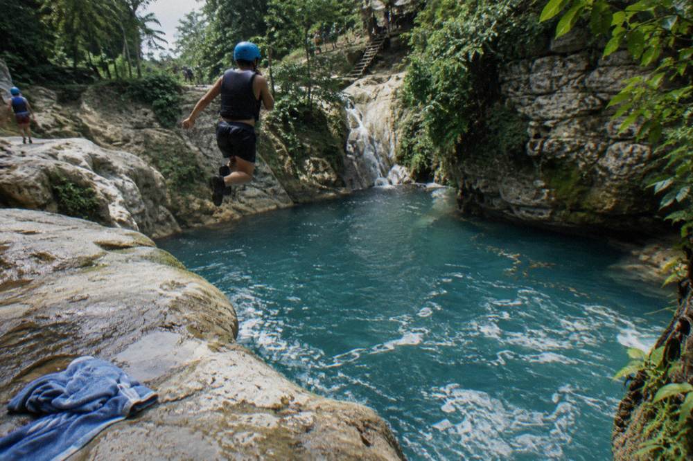 Narrow canyon walls rising above a chain of blue pools along the Damajagua river