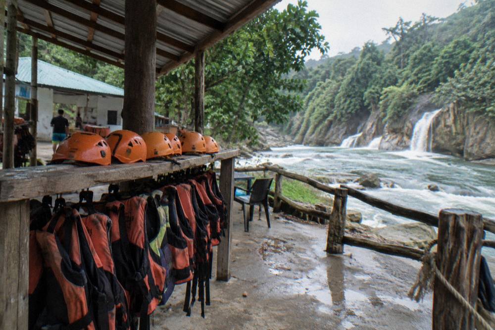 Stack of orange helmets and life vests on a bench at a river visitor centre