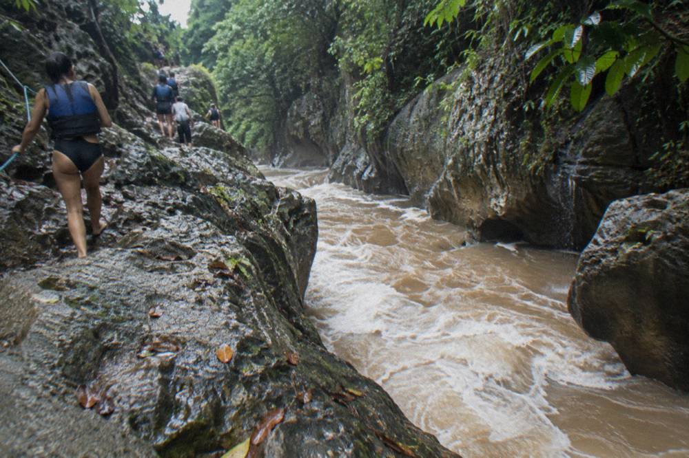 Muddy brown river rushing through a rocky canyon after heavy rain