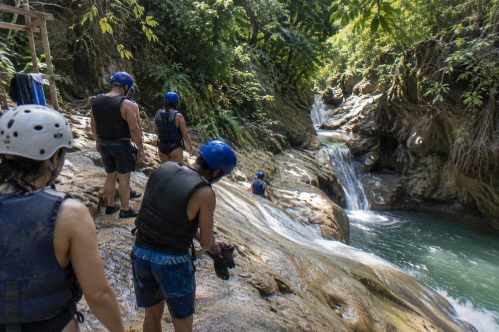 Small group in helmets and life vests waiting at the top of a rock slide