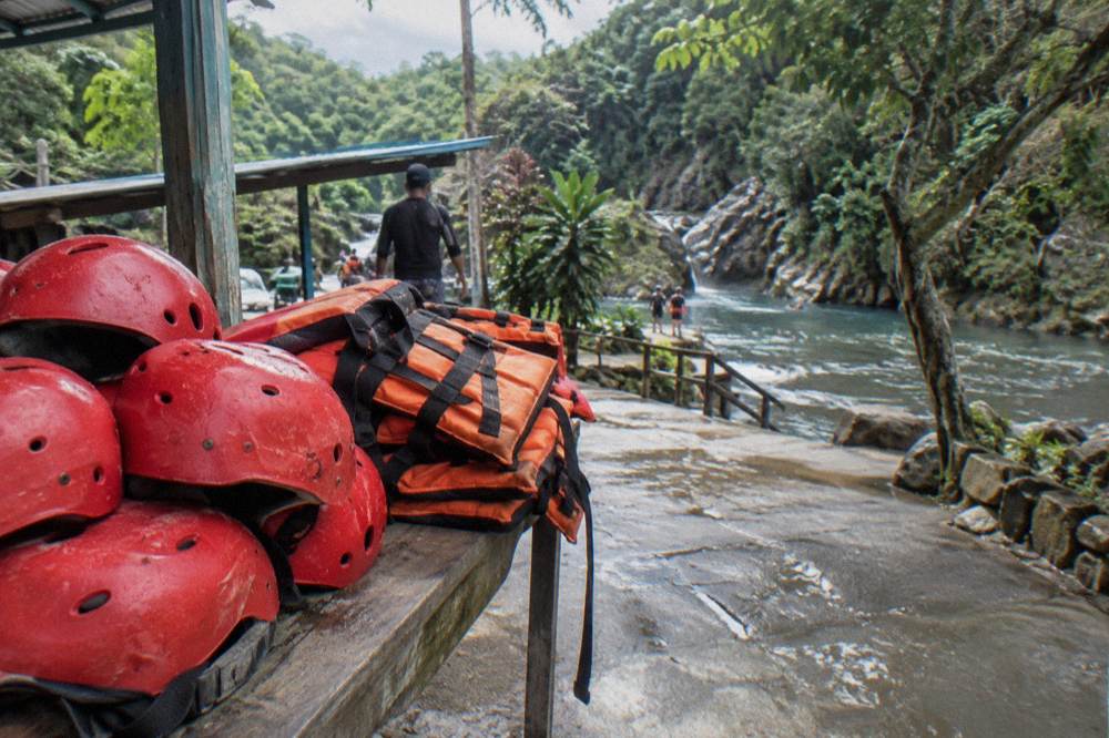 Stack of helmets and orange life vests on a bench at the waterfall base camp