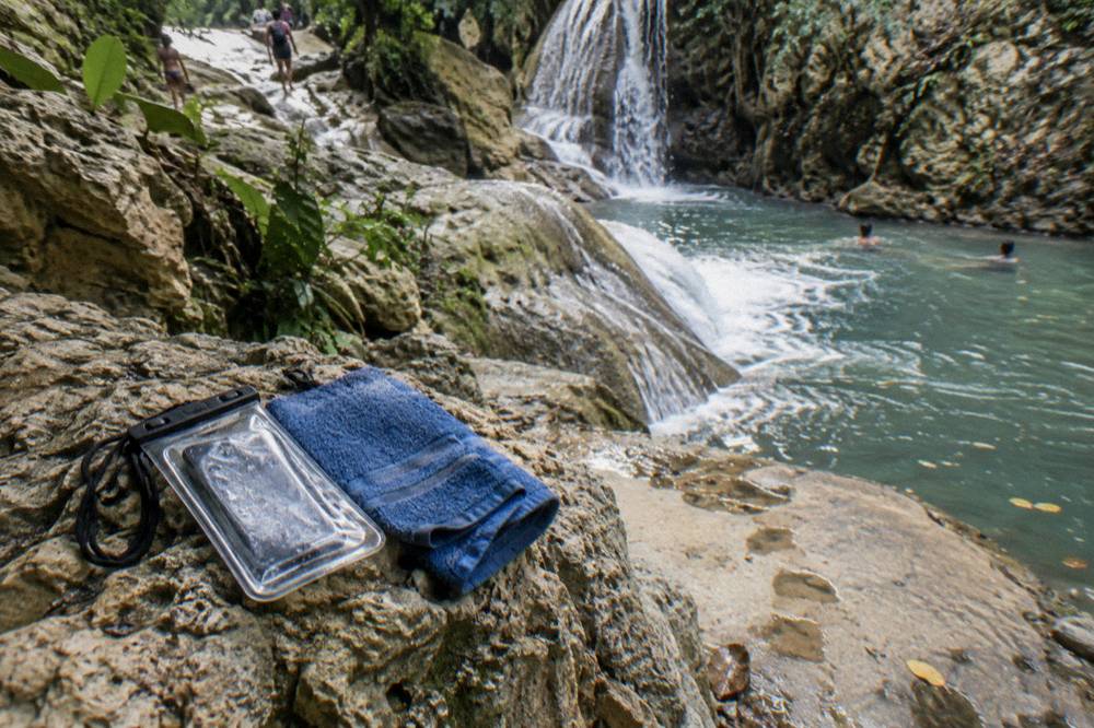 Waterproof pouch and dry belongings stored on a rocky ledge beside the river