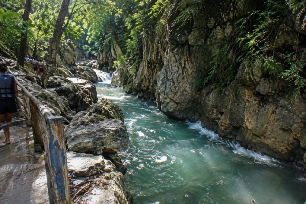 Canyon river running between tall rock walls shaded by trees