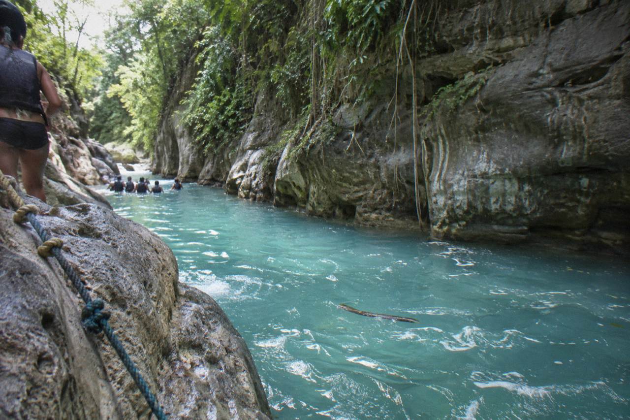 Turquoise waterfall pool in a narrow forest canyon at Damajagua