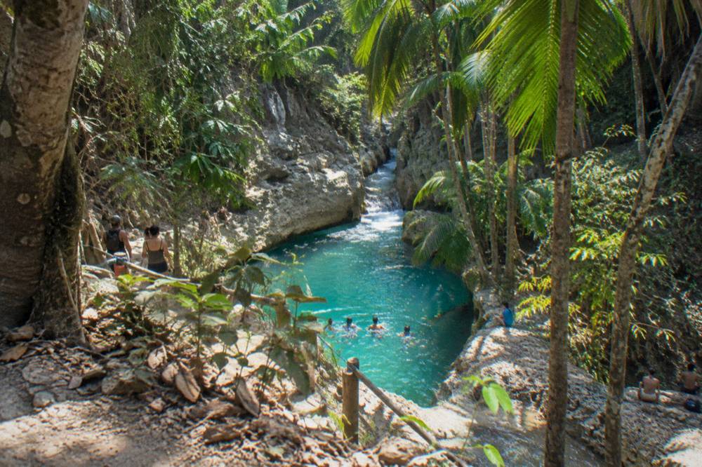 Canyon pool fringed with tropical forest under midday light