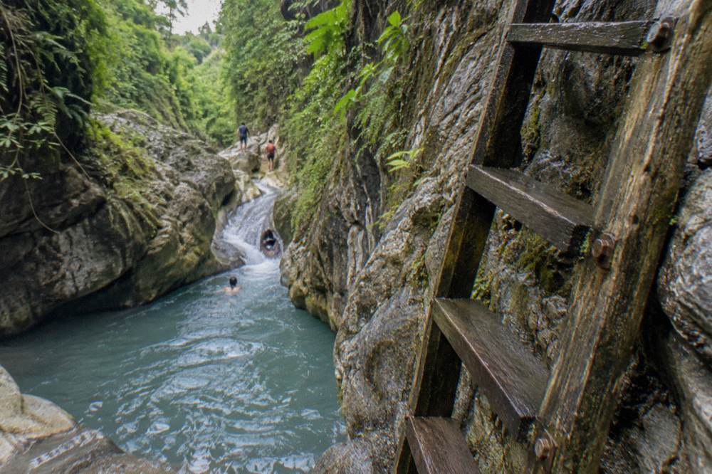 Wooden ladder beside a rock chute at a Damajagua waterfall pool