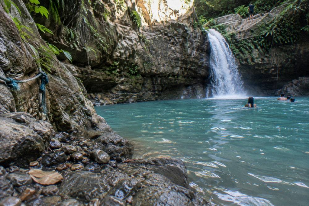 Calm turquoise pool at the base of a canyon waterfall in morning light
