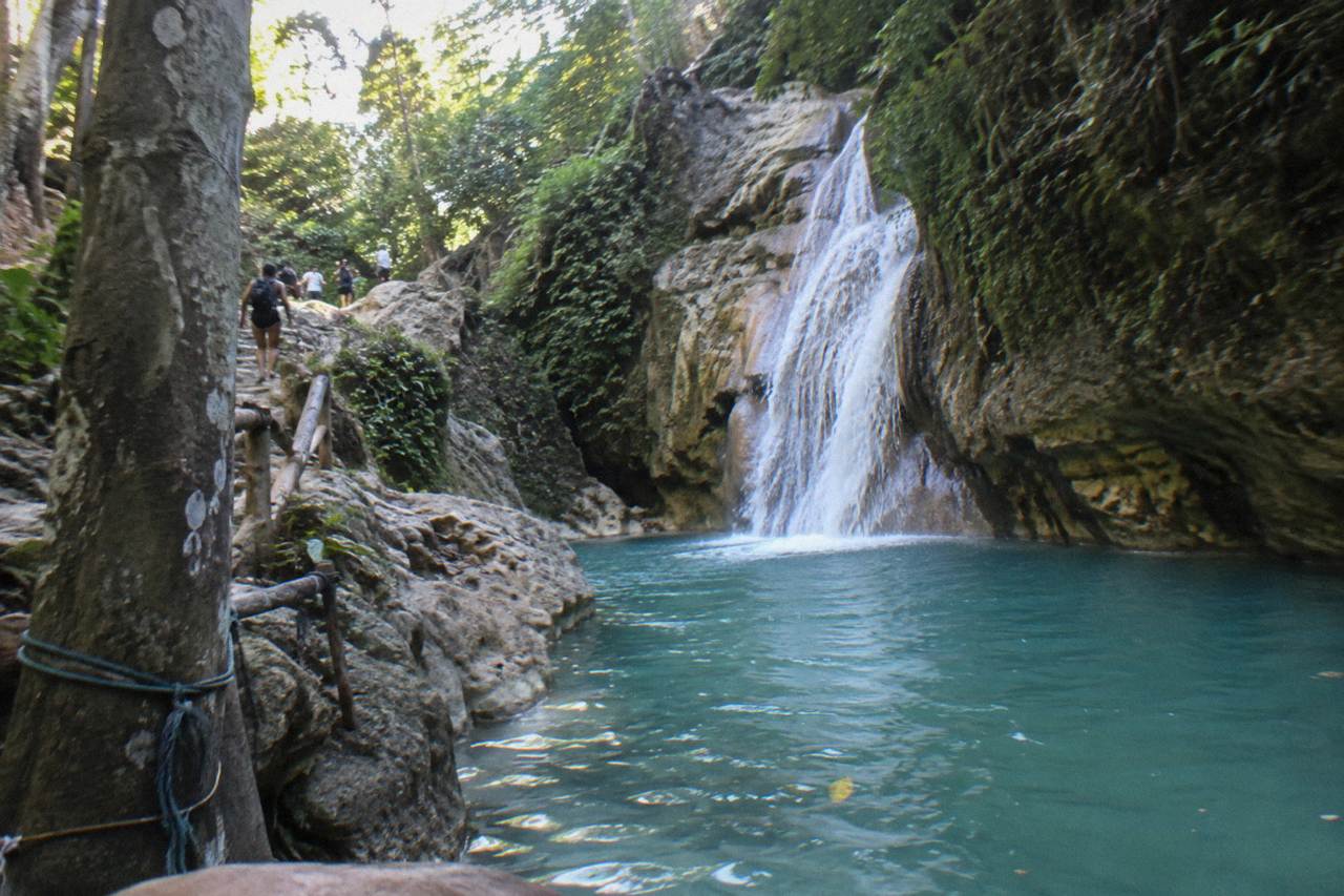 Turquoise waterfall pool in a forested canyon at Damajagua