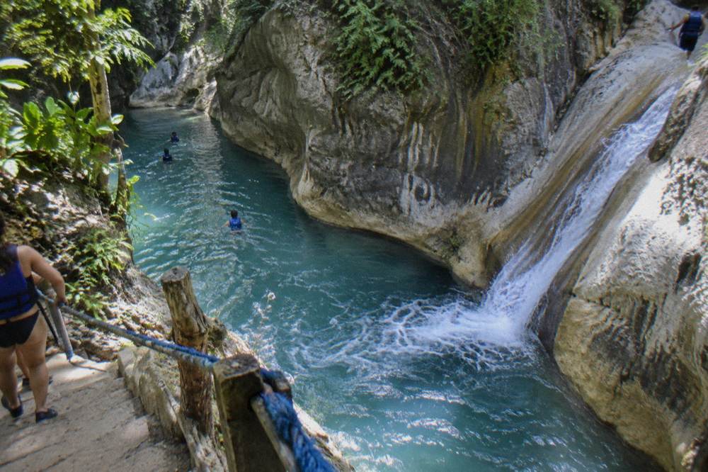 Turquoise waterfall pool between rock walls in the Damajagua canyon