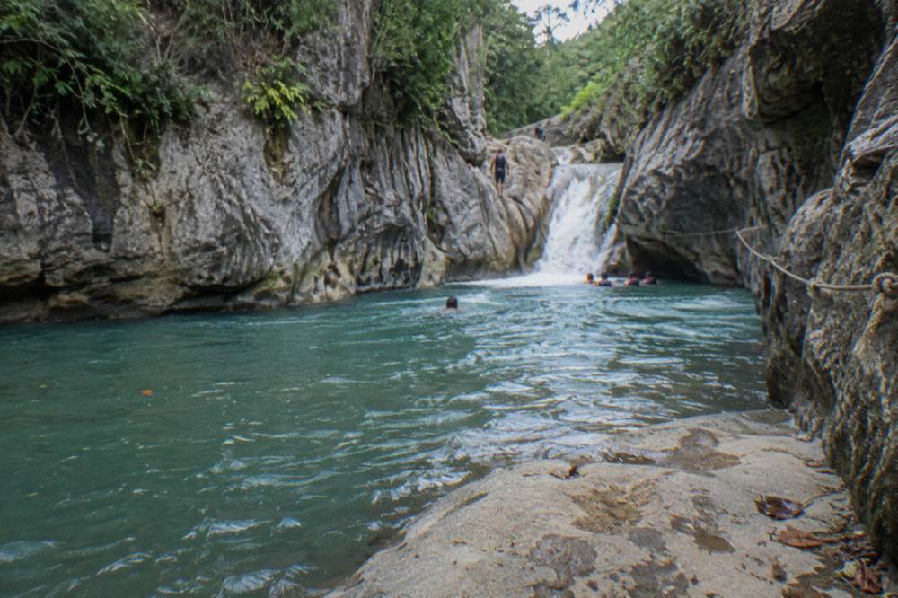 Canyon pool framed by rock walls with a rope line along the edge