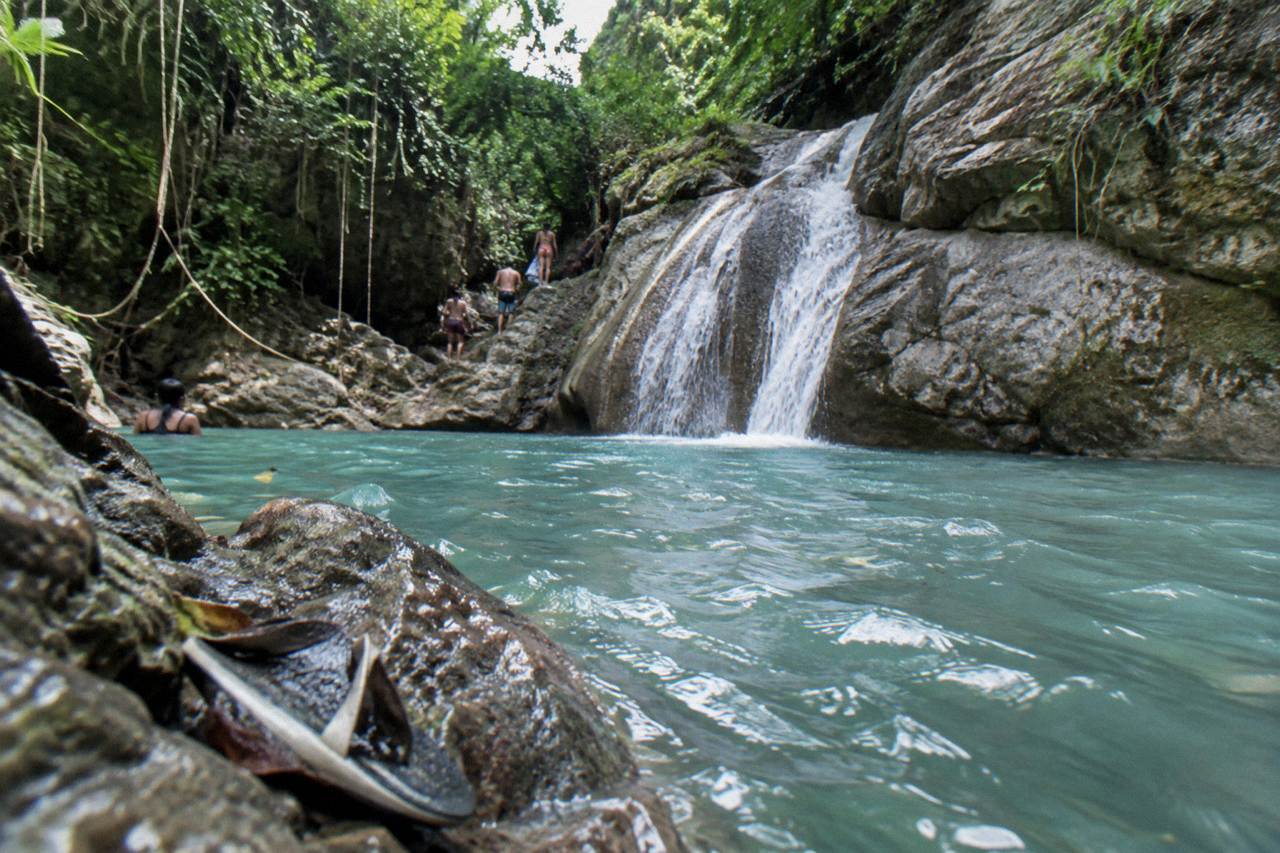Turquoise pool at the base of a jungle waterfall in a narrow canyon