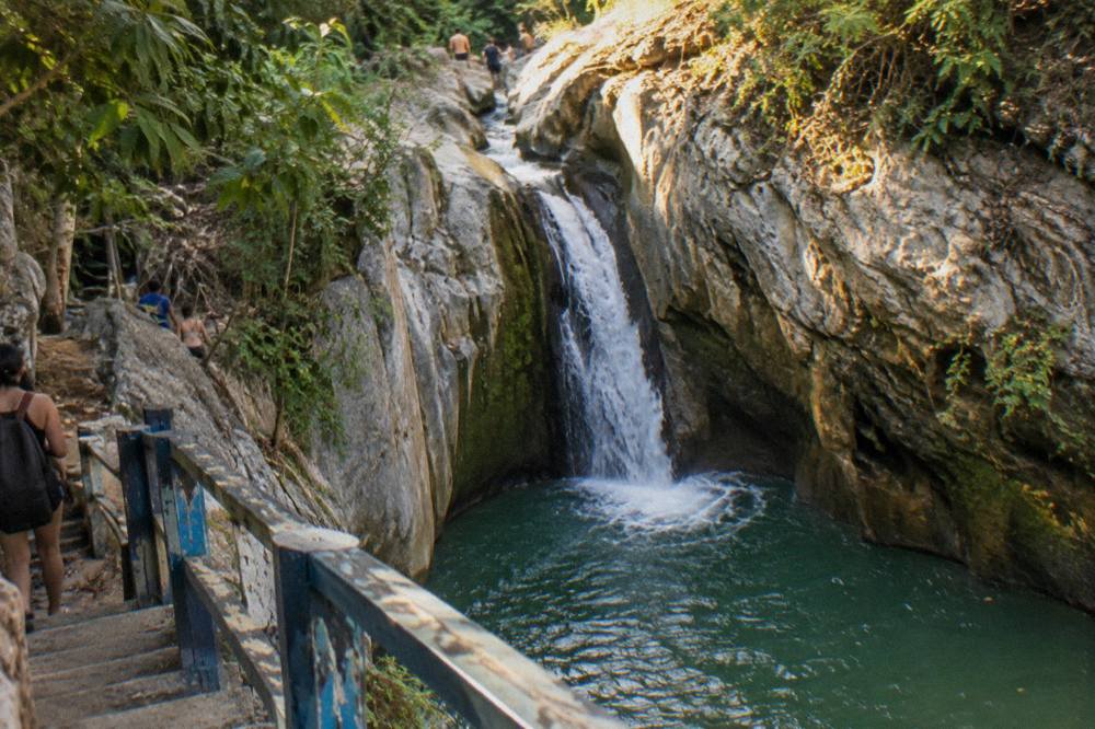 Narrow limestone canyon with a waterfall dropping into a clear green pool