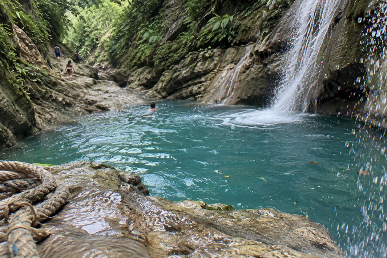 Turquoise pool at the base of a jungle waterfall in a narrow canyon