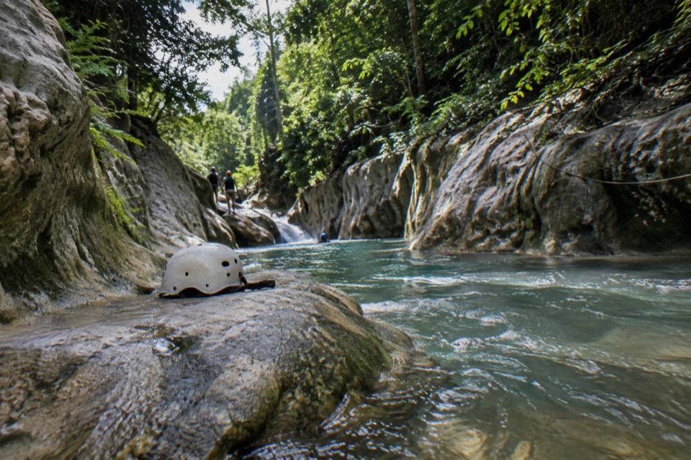 Canyon river running between smooth rock walls shaded by dense green forest